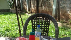 A table set outdoors with a meal consisting of toast, eggs, and a cup of tea, along with condiments and a book. - Maryland Hotel Kisumu (Kisumu)