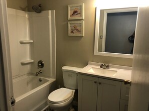 A bathroom with a bathtub, toilet, sink, and a mirror above the sink.