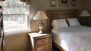 A bedroom with a bed, two bedside lamps, a nightstand, a dresser, and a window with a view of trees. - Cozy comfortable home near lakes, parks and downtown Sumter (Sumter)
