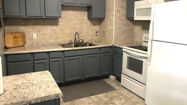 A kitchen with dark gray cabinets, a white refrigerator, a double sink, and a microwave. - Cozy comfortable home near lakes, parks and downtown Sumter (Sumter)