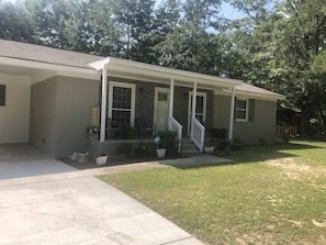 A single-story house with a front porch, a welcome sign, and a small garden area. - Cozy comfortable home near lakes, parks and downtown Sumter (Sumter)