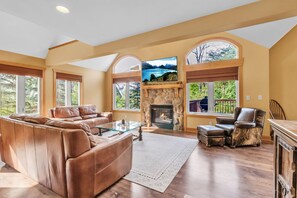 A spacious living room with a fireplace, leather sofa, and a glass coffee table. - Luxury Chalet • Fire Pit• Game Room • Sleeps 14 ~ Virtual Tour Included! (Great Valley)