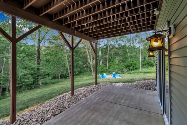 A covered patio area with a view of a backyard and a house. - Luxury Chalet • Fire Pit• Game Room • Sleeps 14 ~ Virtual Tour Included! (Great Valley)