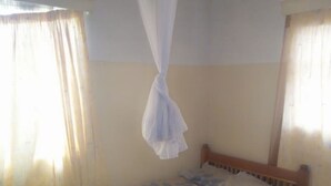 A single bed with a wooden headboard, a white canopy, and a floral bedspread. - Banana Leaf Hotel (Nyeri)