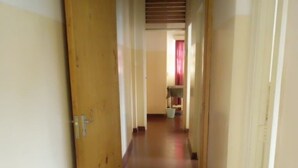 A narrow hallway with a wooden door on the left and a white door on the right. - Banana Leaf Hotel (Nyeri)
