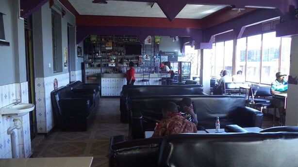 A restaurant with booths and a bar area. - Millennium Guest House (Narok)