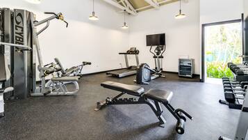 A gym with various exercise equipment, a bench, and dumbbells.