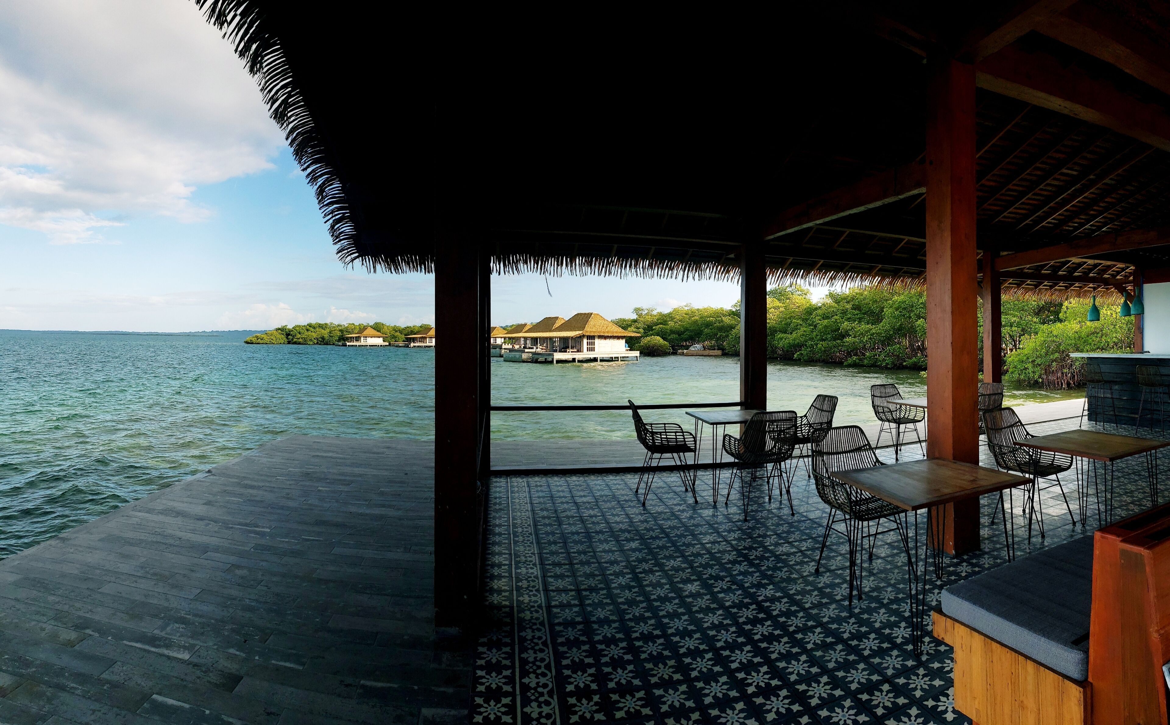 Un área de comedor al aire libre con vista a una isla tropical y el agua.