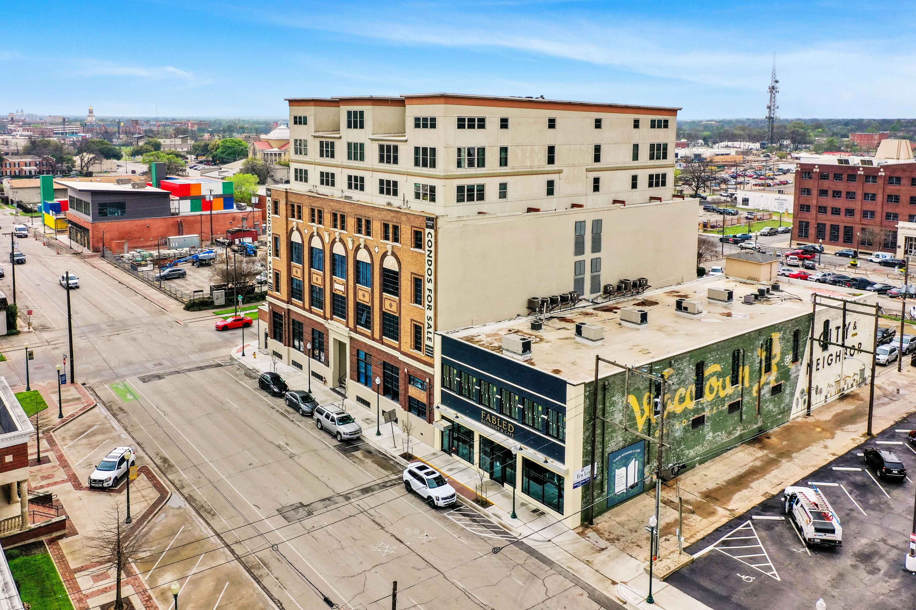 A multi-story building with a modern facade, a parking lot, and a street view.