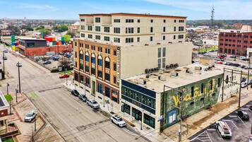 A multi-story building with a modern facade, a parking lot, and a street view.