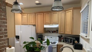 A modern kitchen with wooden cabinets, a stainless steel sink, a white refrigerator, a stove, and a microwave. - Three Bedroom, Sanitized, Pet Friendly Bungalow (St. Augustine)