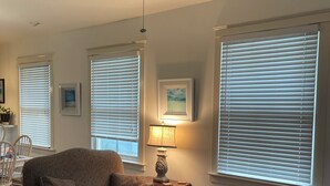 A living room with a ceiling fan, a sofa, a patterned armchair, and a table with a lamp. - Three Bedroom, Sanitized, Pet Friendly Bungalow (St. Augustine)