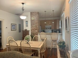 Cozy dining area with a central table and six chairs, surrounded by a stone accent wall and ceiling fan.
