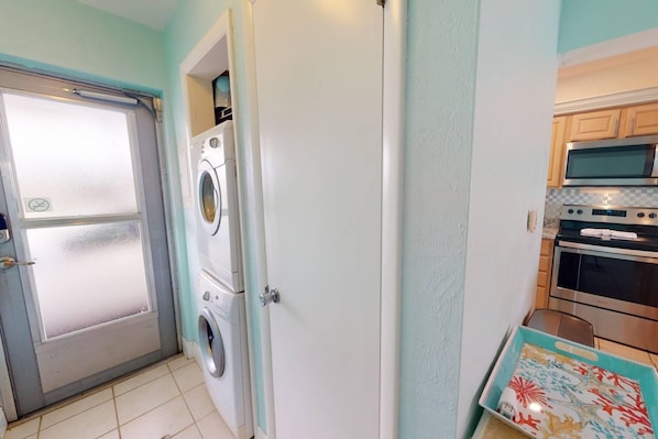 A compact kitchen with a washing machine, a microwave, and an oven.