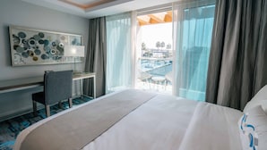 A hotel room with a large bed, a desk, and a view of a pool and palm trees. -  H2O Hermosa Beach Hotel (Hermosa Beach)