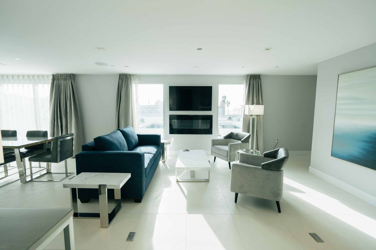 A modern living room with a blue sofa, a white coffee table, and a grey armchair.