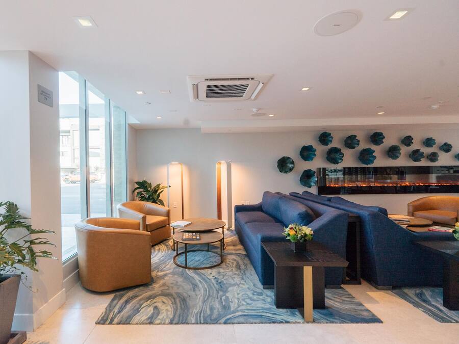 A modern lobby with a blue sofa, a round coffee table, and a potted plant.