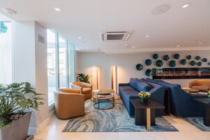 Un vestíbulo moderno con un sofá azul, una mesa de centro redonda y una planta en maceta.
