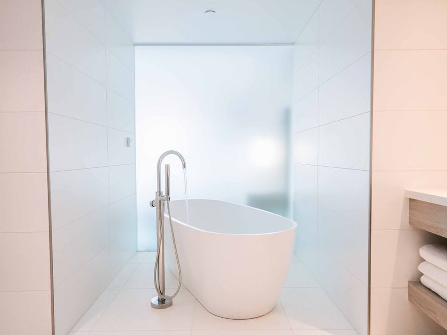 A modern bathroom with a freestanding bathtub, a shower, and a wooden vanity with towels.