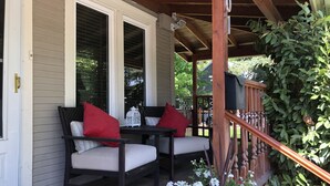 En veranda med två stolar och ett bord, ett träräcke och en brevlåda.