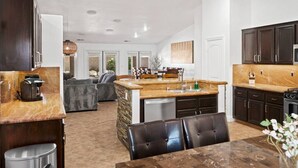 A modern kitchen with dark wood cabinets, a marble countertop, and a central island with seating.