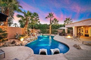 A swimming pool with a hot tub, surrounded by palm trees and a sunset sky. - The Luxe House | Resort Style Backyard (Indio)