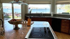 A kitchen with a large island, a view of the sea, and a dining area with outdoor seating.