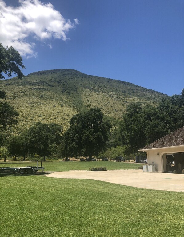 A grassy area with a building that has a garage. There is a hill in the background.