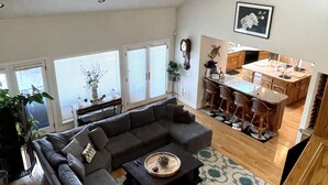 A spacious living area with a large sectional sofa, a dining table with chairs, and a kitchen in the background.