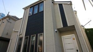 A modern building with a flat roof, large windows, and a door with a sign. - COCO Shinjuku (Tokyo)