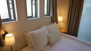 A hotel room with a bed, a nightstand, a lamp, and two windows. - COCO Shinjuku (Tokyo)