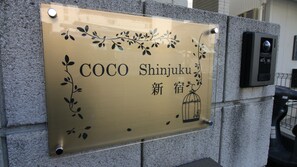 A sign with the name "COCO Shinjuku" and a birdcage symbol, mounted on a stone wall. - COCO Shinjuku (Tokyo)