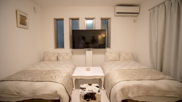 A bedroom with two beds, a TV, and an air conditioner. - COCO Shinjuku (Tokyo)