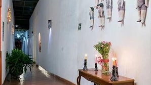 A hallway with a tiled floor, a wooden table with candles, and wall-mounted dolls.
