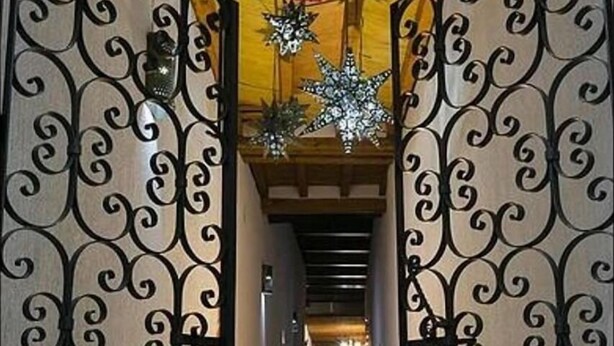 A corridor with ornate wrought iron gates, a red spherical ornament, and decorative star-shaped lights.