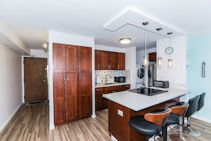 Eine moderne Küche mit Holzausstattung, einer integrierten Mikrowelle und einer Bar mit Barhocker.