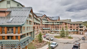 Un hôtel à plusieurs étages doté d’une cour intérieure, avec une façade combinant des éléments en bois et en pierre, et proposant différents types de chambres, dont certaines avec balcon et de grandes fenêtres.