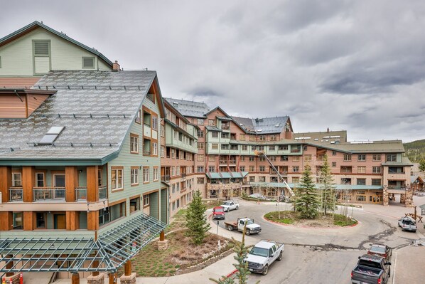 Un hotel de varios pisos con un patio central, que presenta una combinación de fachadas de madera y piedra, y diversos diseños de habitaciones con balcones y amplias ventanas.
