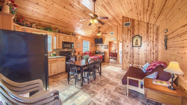 A wooden cabin interior with a kitchen, dining area, and a cozy seating area. - Wine Cup Rr9122wc 1 Bedroom Home by RedAwning (New Braunfels)