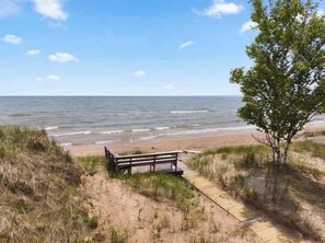 A bench on a sandy path leading to a beach with the ocean in the background.