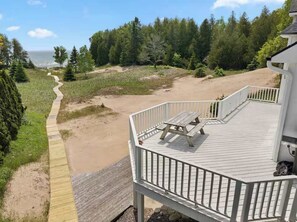 Eine Holzterrasse mit Picknicktisch, mit Blick auf Strand und Waldgebiet.