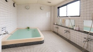 Une salle de bain avec une baignoire, une fenêtre et des murs carrelés.