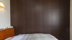 Une chambre d’hôtel avec une tête de lit en bois, un lit avec une literie blanche et une couverture à carreaux.