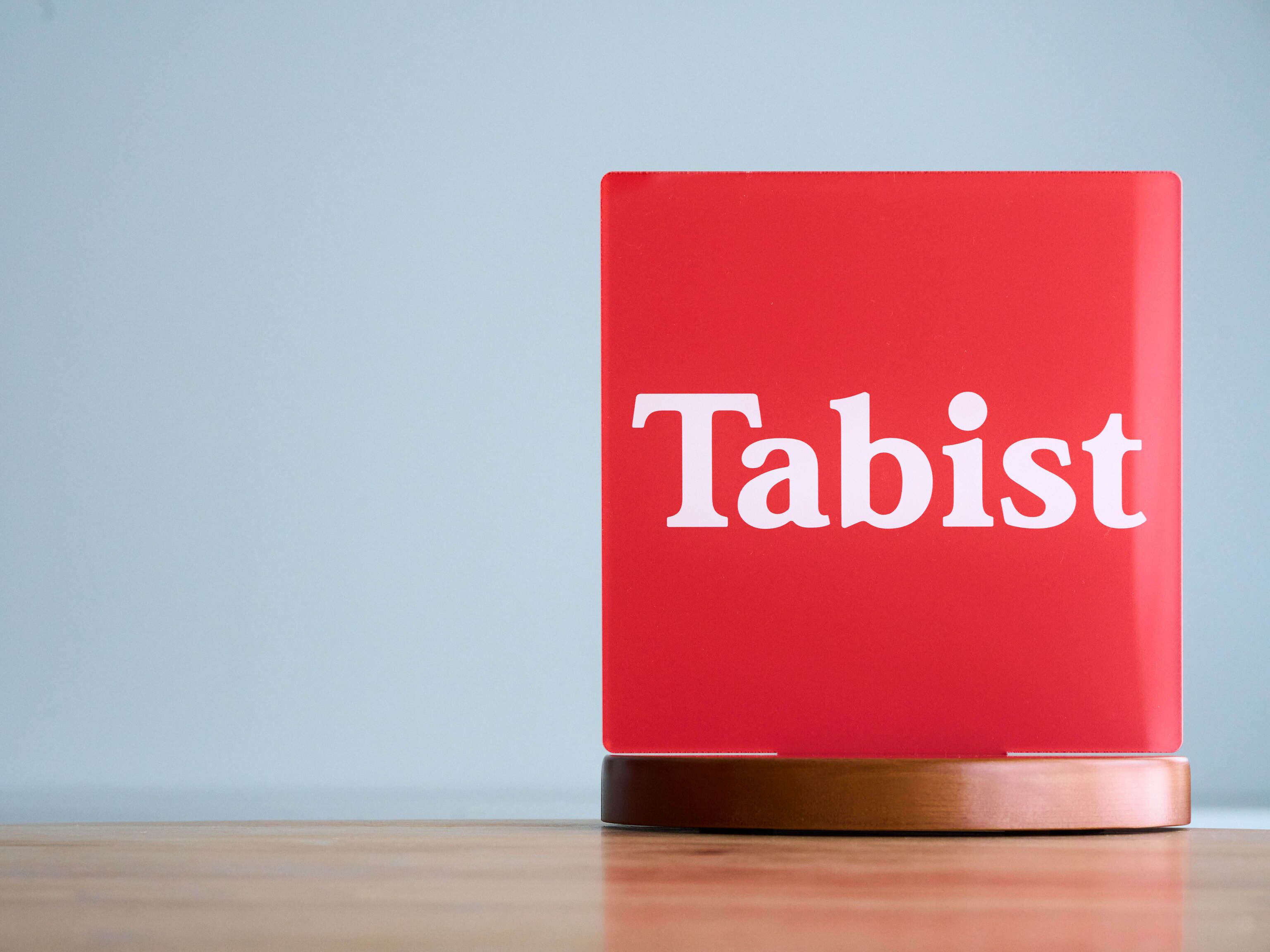 Una laptop roja con la palabra "Tabist" sobre una superficie de madera.