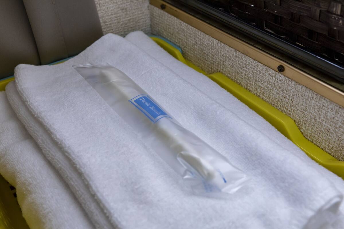 A stack of white towels with a blue label in a yellow container.
