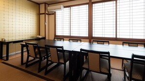 Une salle de conférence avec une longue table, des chaises, un téléphone et une grande fenêtre à motifs géométriques.
