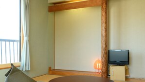 A traditional Japanese room with tatami flooring, a low wooden table, and a television on a cabinet.