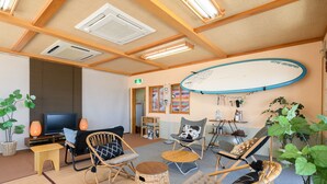 A cozy room with wicker furniture, a flat-screen TV, and a surfboard on the wall.