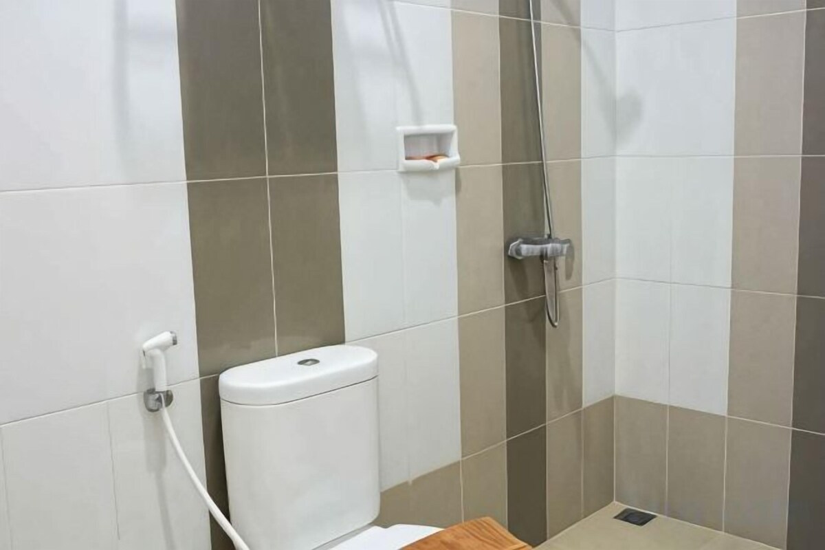 A bathroom with a toilet, a shower, and a small shelf.
