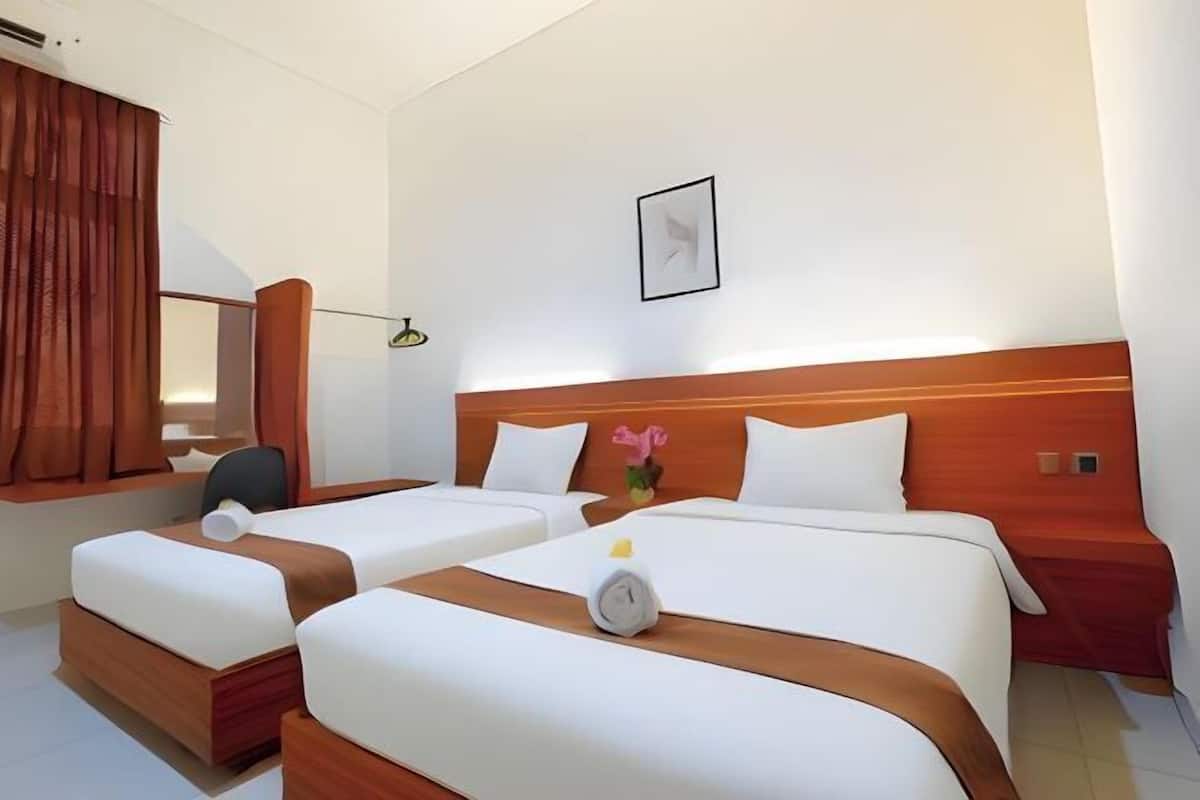 A hotel room with two beds, a desk, a chair, and a window with curtains.